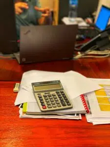 A calculator rests atop financial documents on a desk, illustrating essential tools and preparation steps for implementing outsourced bookkeeping in 2025.