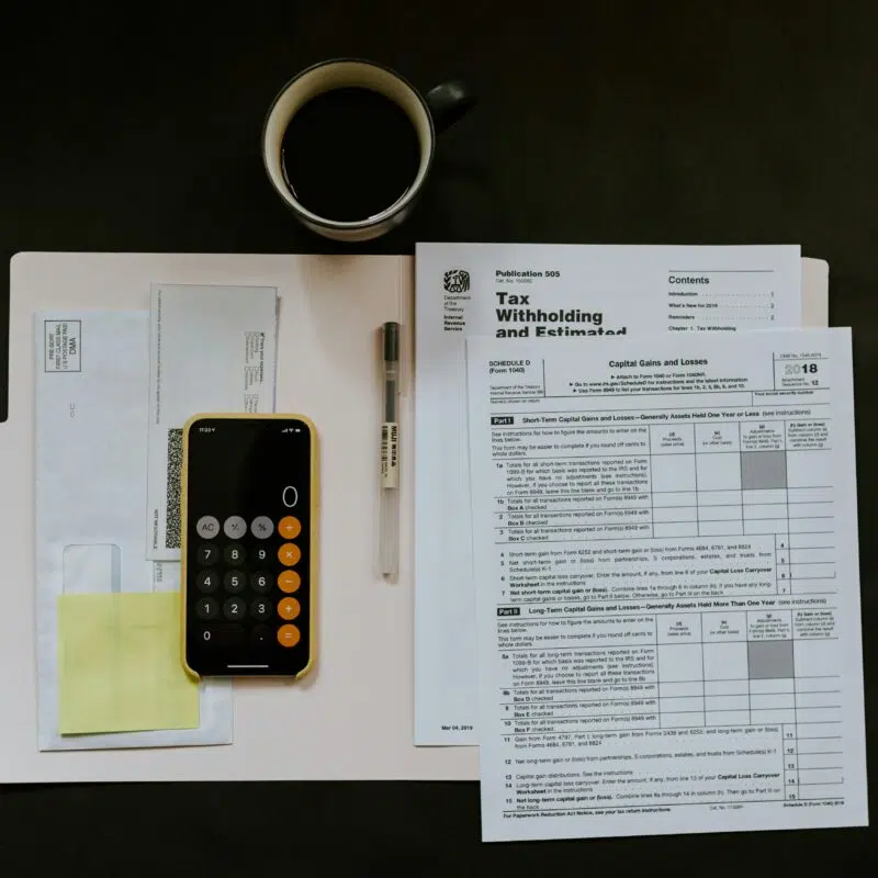 A tax document, calculator, and coffee cup laid out on a table illustrate organized strategies for managing tax liabilities effectively.