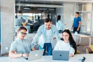 A collaborative team reviews performance data on laptops, symbolizing real-time tracking of KPIs and ROI insights through dashboards in 2025.