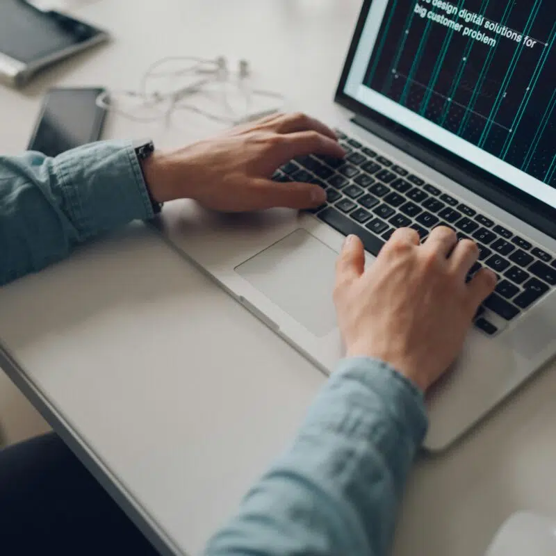 Hands typing on a laptop displaying digital financial metrics.