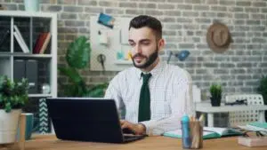 A fractional CFO works remotely on a laptop in a modern office, reflecting flexible engagement models and virtual finance leadership trends in 2025.