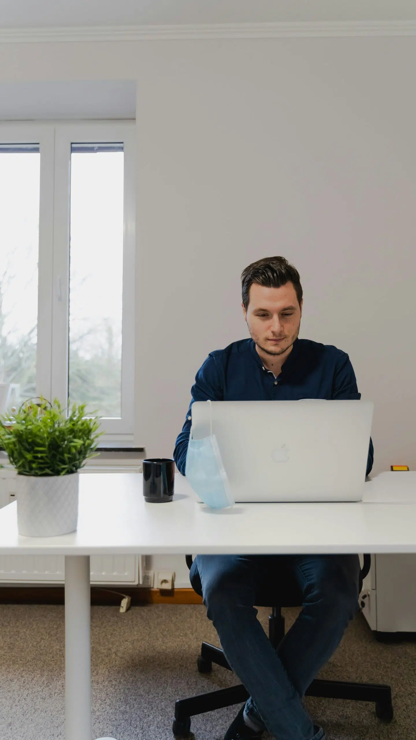 A man sitting at a desk with a laptop, analyzing financial management solutions.