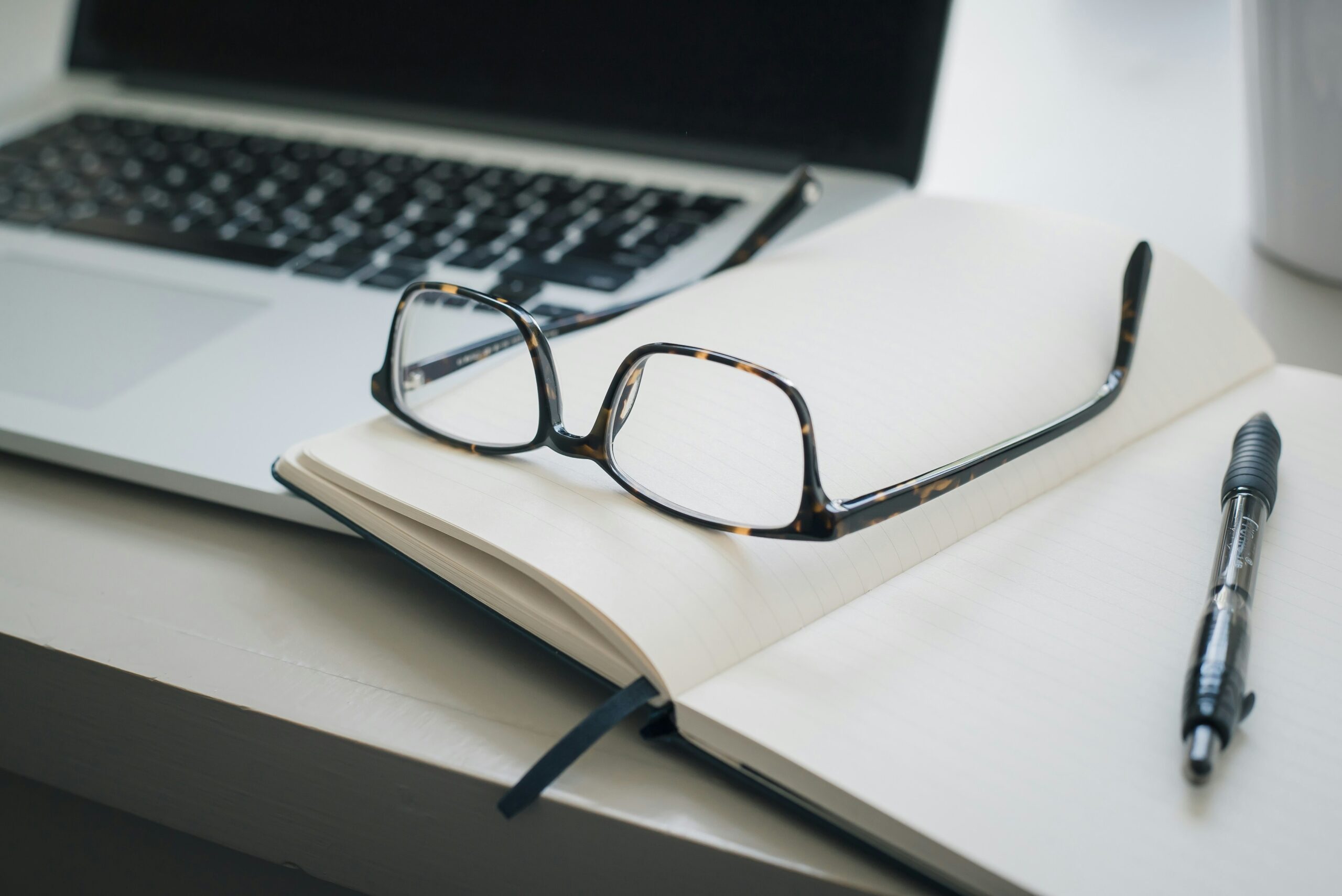 an open notebook with pen and glasses | Cohesion an open notebook with pen and glasses