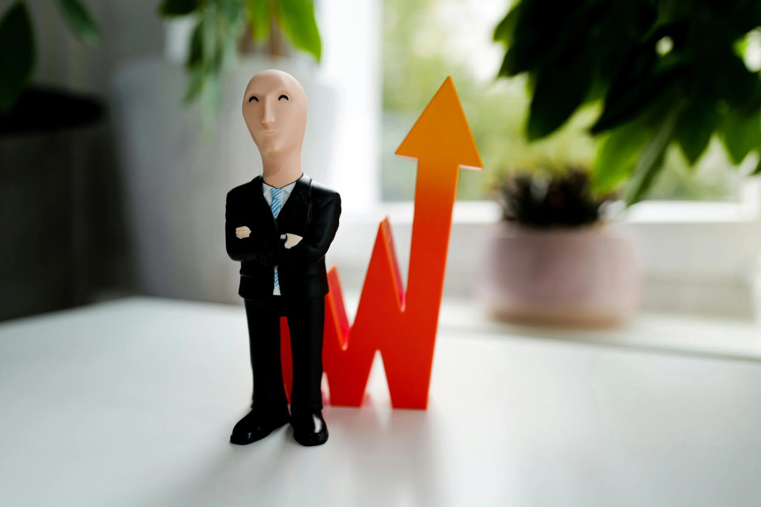 A figurine of a confident businessperson stands beside an upward-pointing arrow, symbolizing financial forecasting and proactive risk planning. | Cohesion A figurine of a confident businessperson stands beside an upward-pointing arrow, symbolizing financial forecasting and proactive risk planning.