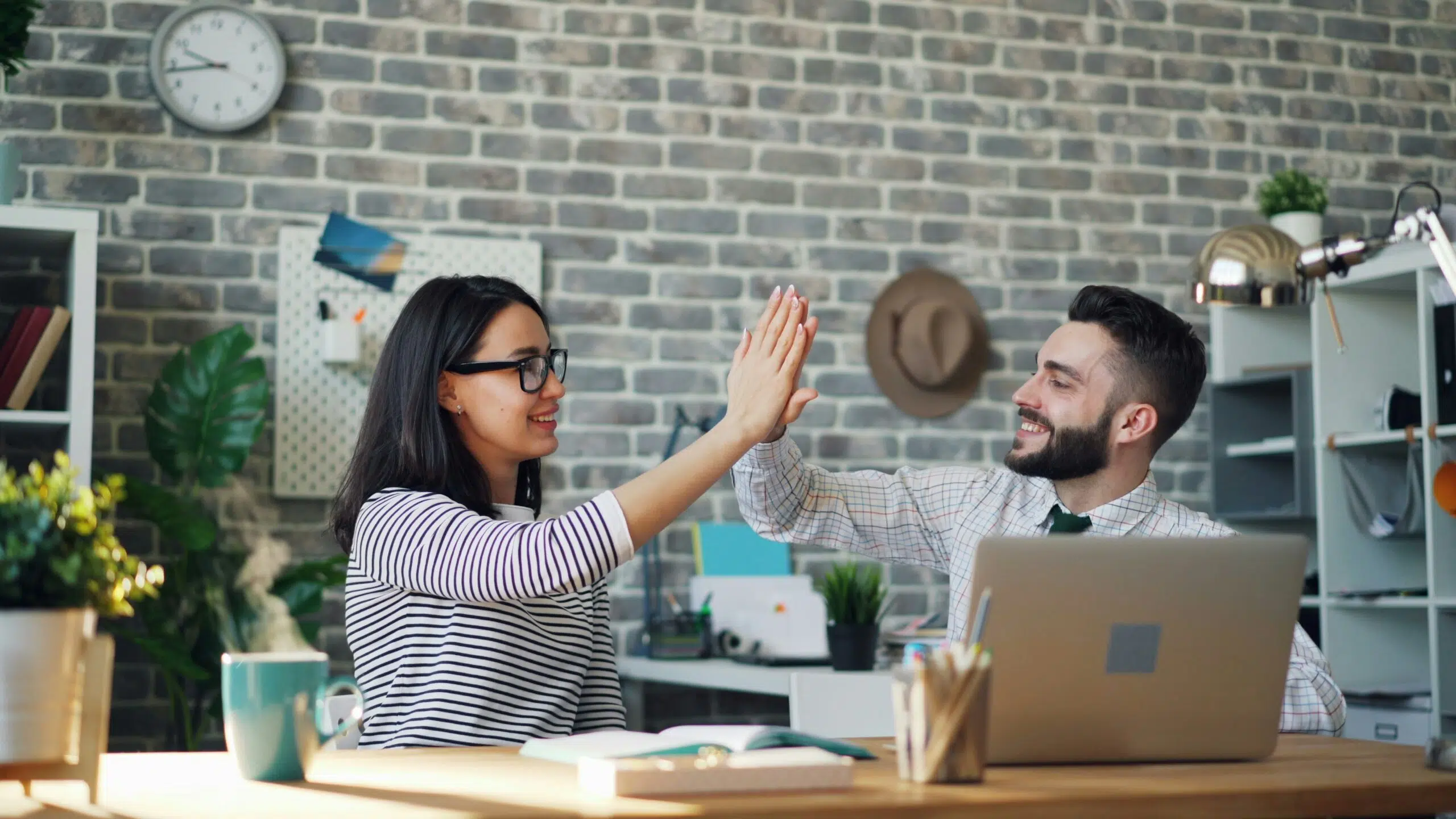 Two colleagues smiling and high-fiving in an office, symbolizing success after implementing effective tax planning strategies. | Cohesion Two colleagues smiling and high-fiving in an office, symbolizing success after implementing effective tax planning strategies.