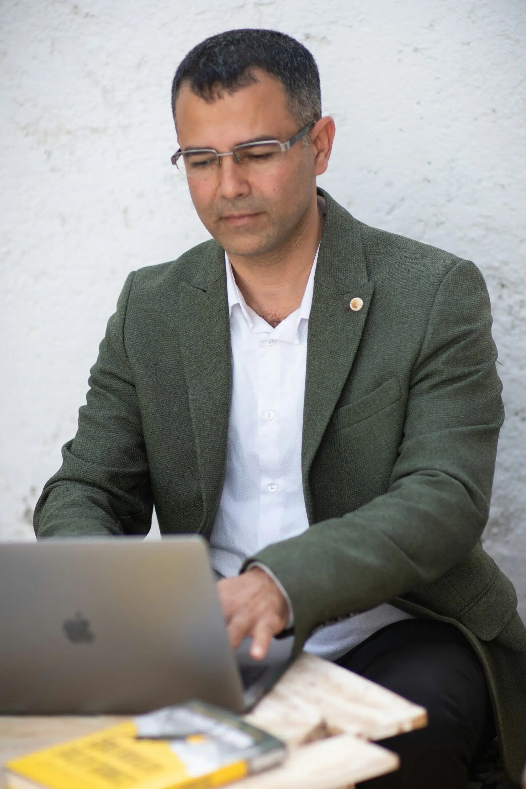 Professional reviewing documents on a laptop outdoors. | Cohesion Professional reviewing documents on a laptop outdoors.