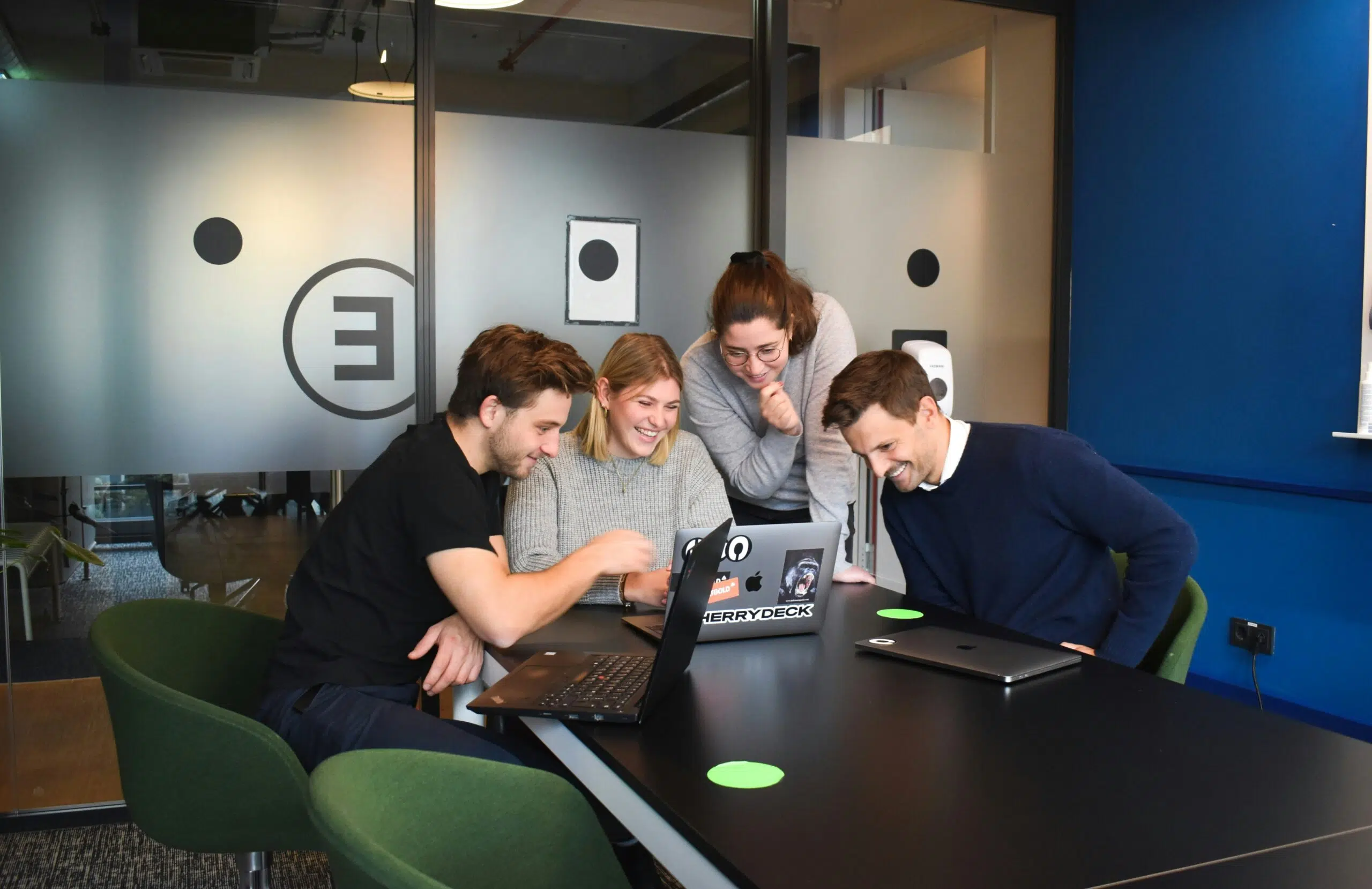 Team collaboration around laptop in modern office | Cohesion Team collaboration around laptop in modern office