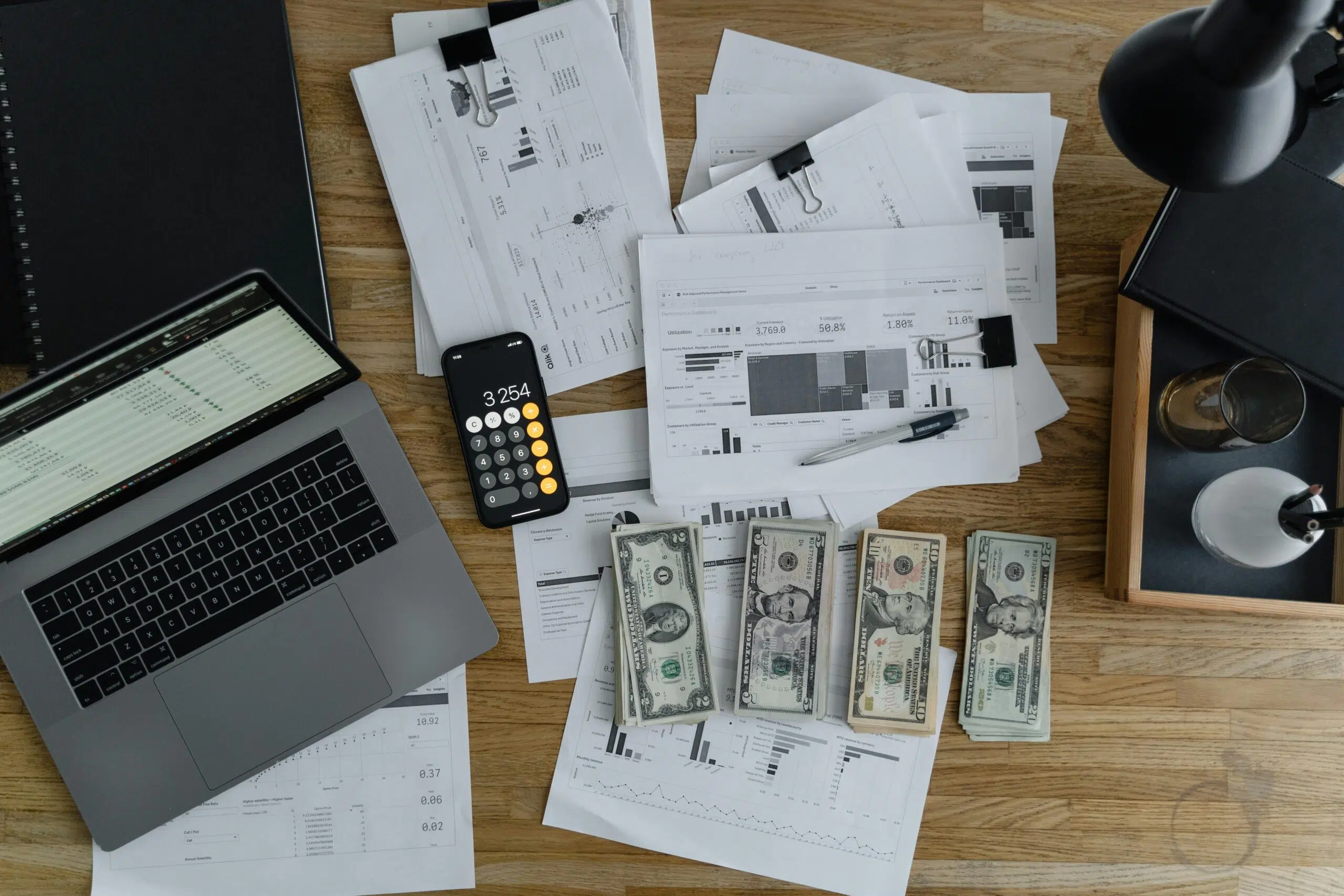 workplace desk with laptop, accounting papers and cash